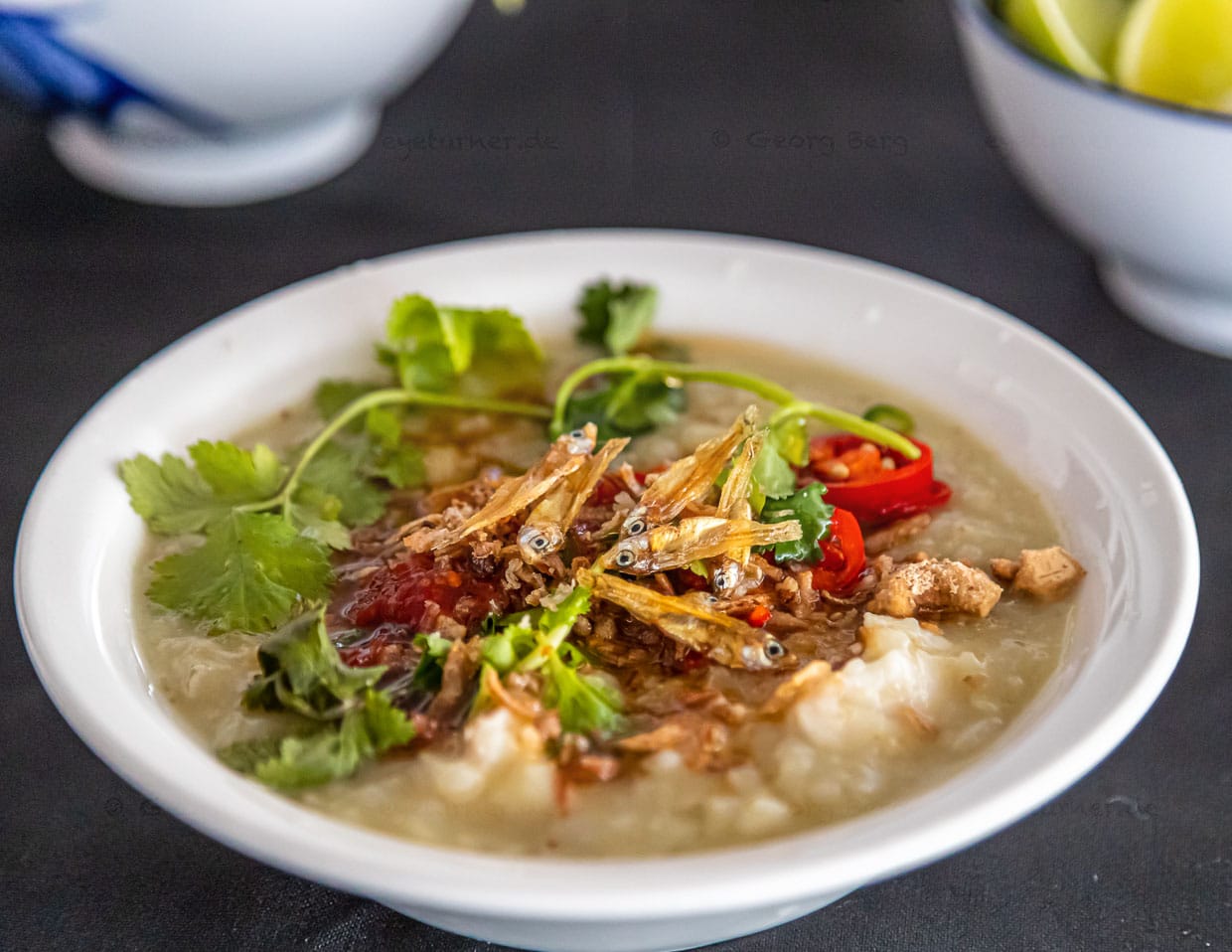 Fisch-Congee mit verschiedenen Würzzutaten wie frittierten Anchovis, Chillies, Ingwer, Knoblauch, Erdnüssen, Sesam, Sojaöl und verschiedenen Gemüsen / © Foto: Georg Berg