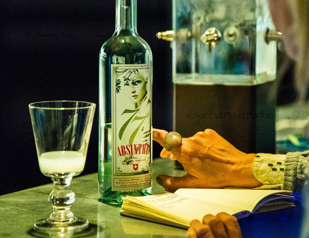 Im Maison de l’Absinthe wird man an einer Bar empfangen. Hier ist auch stets eine kalte Quelle im Einsatz. Früher tropfte das eiskalte Wasser mit der Geschwindigkeit von einem Tropfen pro Minute über den Zuckerwürfel und durch den Löffel in den zimmerwarmen Alkohol. Jeder Tropfen hinterlässt milchig-grüne Trübungen im Glas / © Foto: Georg Berg