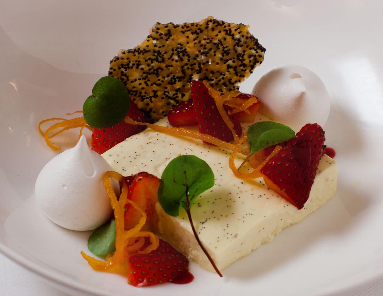 Vanille-Panacotta mit Grappa, Erdbeeren und Baiser. Die Panacotta hat ein sehr intensives Vanille-Aroma. Orangenzesten sorgen für eine leichte und angenehme Bitternote und im Knusperchips sorgt Mohn für den richtigen Crunch / © Foto: Georg Berg