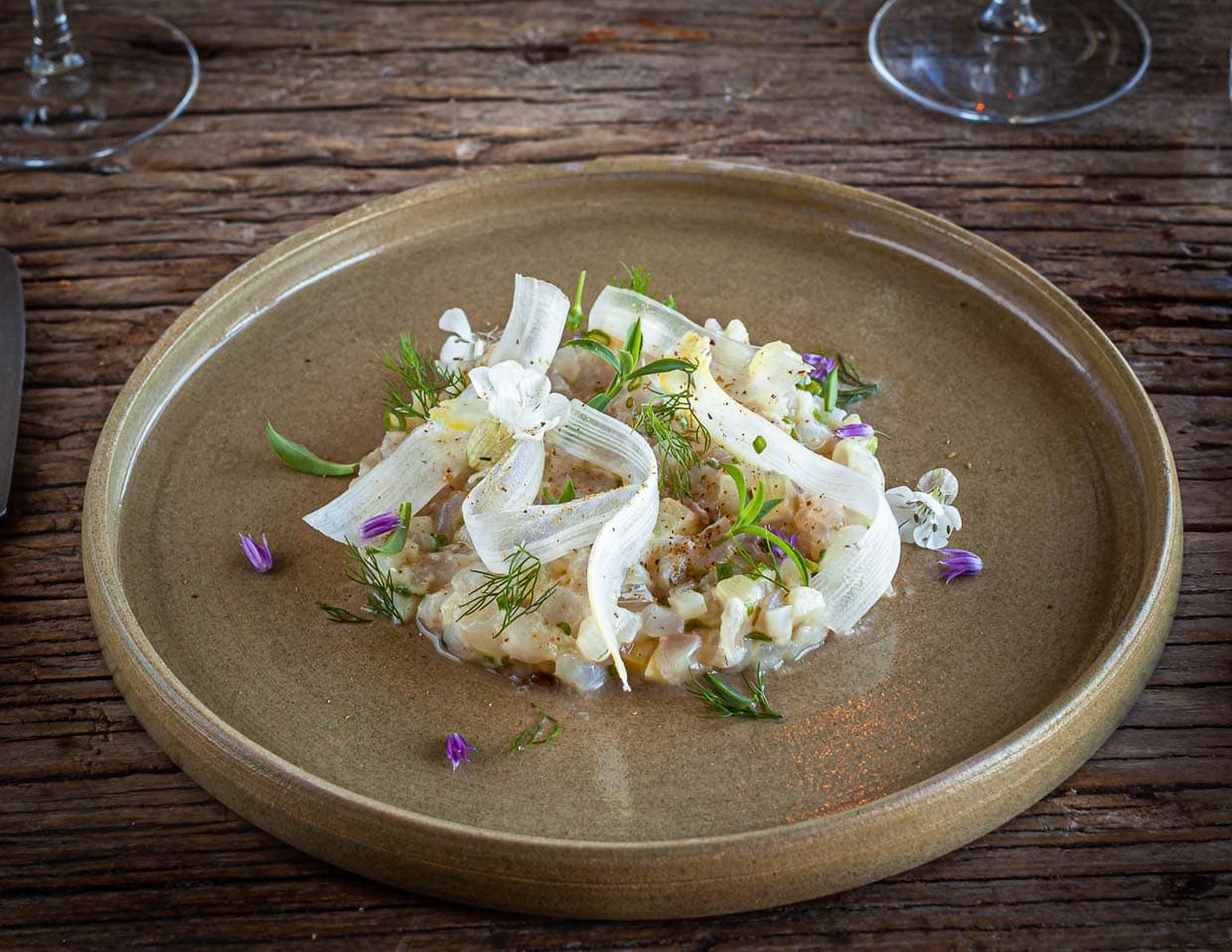 Die marinierte Seebrasse wird mit frisch gesammelten Kräutern von der nahe gelegenen Meeresklippe angerichtet / © Foto: Georg Berg