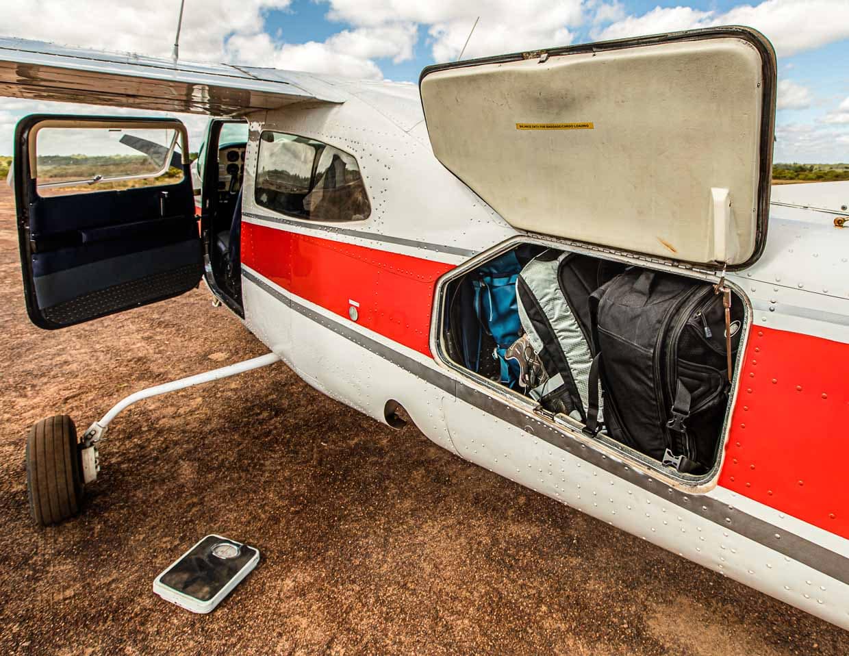 Nicht nur das Gepäck wird gewogen. Alle Passagiere bekommen in der Cessna 210 ihren Sitzplatz nach dem Gewicht zugewiesen, das sie auf die Waage bringen. Je besser das Gewicht verteilt ist, desto stabiler liegt später die Maschine in der Luft / © Foto: Georg Berg