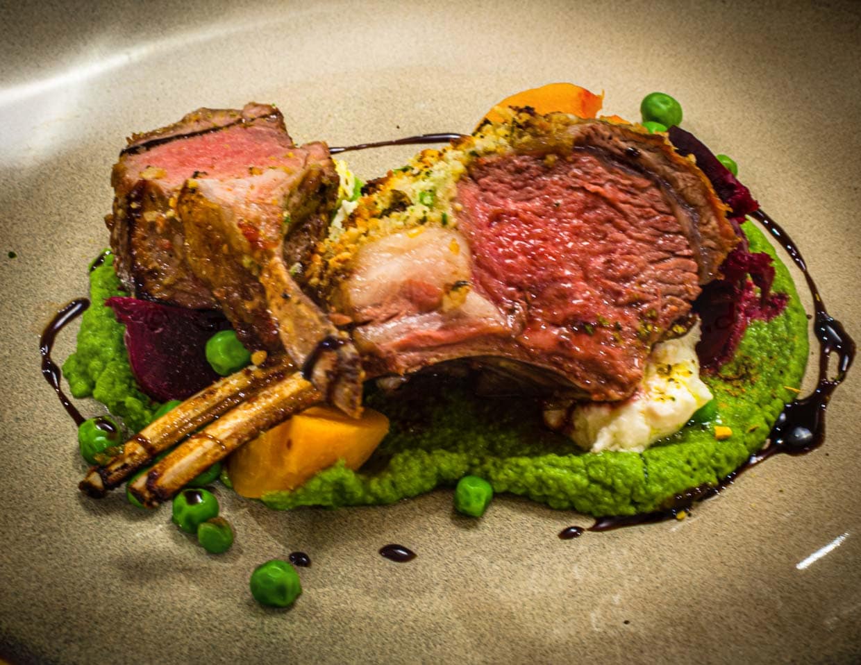 Und so kommt es dann köstlich mit tasmanischem Pfeffer und Vincotto gewürzt auf den Tisch: Lammkarree in der Pinienkruste mit Schafskäse an Erbsen-Mint-Püree / © Foto: Georg Berg
