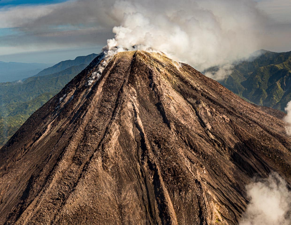 Während wir uns aus der Luft nähern, stößt der Bagana Vulkan Rauchwolken aus / © Foto: Georg Berg