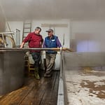 Kurz bevor sich das Brauhaus mit dichtem Nebel füllt steht Zoigl-Braumeister Sepp Neuber mit einem Hausbrauer am Schiff / © Foto: Georg Berg