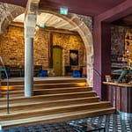 Jeder Bogen ist ein Geschenk, sagt Mitinhaberin Kirstin Kleinkauf. Dieser Bogen, der den Eingangsbereich mit Bistro und Bar verbindet, ist ein besonderer Blickfang, an dem kein Gast achtlos vorbeigeht. Eine kleine Beobachtung am Rande: Beim Betreten der Bar interessieren sich die Männer mehr für die Statik des alten Steins, während die Frauen ihren Blick über die samtigen Sessel und funkelnden Lampen schweifen lassen / © Foto: Georg Berg