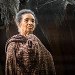 Frau in traditioneller Kleidung vor einer Hütte in Wologai, Indonesien / © Foto: Georg Berg