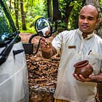 Buddhistischer Segen für eine gute Reise. Während hinten die Koffer verladen werden, sprenkelt der Hotelmanager Wasser mit Blütenblättern auf die Fahrzeugfront. Damit soll das nächste Ziel heil erreicht werden / © Foto: Georg Berg