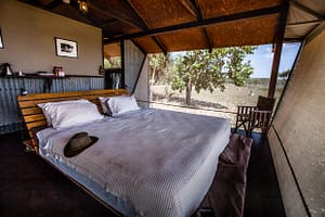 Doppelbett im australischen Outback-Chic hinter den Wellblechwänden der Bamurru Plains Lodge. Wind weht durch die Fliegengitter und keiner vermisst Klimaanlage oder WLAN / © Foto: Georg Berg
