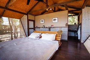 Doppelbett im australischen Outback-Chic hinter den Wellblechwänden der Bamurru Plains Lodge. Wind weht durch die Fliegengitter und keiner vermisst Klimaanlage oder WLAN / © Foto: Georg Berg