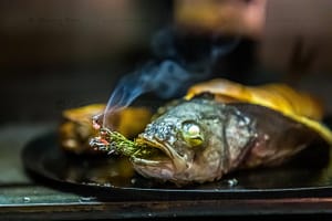 Der Loup de Mediterranée gefüllt mit einem zart getrüffelten Souffle von Cyril Aveline räuchert sich noch im Jospergrill selbst mit einem Rosmarinzweig / © Foto: Georg Berg