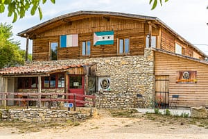 Die Schokoladen-Manufaktur Frigoulette liegt im Dorf Beaufort-sur-Gervanne mitten im Naturpark Vercors. Eine kurvige Straße führt aus dem Dorf heraus Richtung Frigoulette. Die Manufaktur ist nach dem Land benannt, auf dem die Familie von Bernard Xueref seit Generationen Landwirtschaft betreibt. Über dem Eingang des Holzbaus hängen die Flaggen von Frankreich und São Tomé & Principe / © Foto: Georg Berg