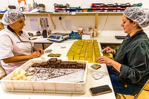 Am kühlen Vormittag wird der Bestseller der Schokoladen-Manufaktur Frigoulette von Hand in goldenes Papier verpackt. Malakoff-Pralinen, Nuss-Nougat-Pralinen mit 68  Kakaoanteil und gerösteten Haselnüssen. Im Sommer läuft die Produktion für Weihnachten. Frigoulette beliefert Geschäfte in ganz Frankreich mit Malakoff-Pralinen / © Foto: Georg Berg