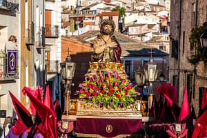 Prozession in Spanien mit Jesusfigur auf einem Wagen und Teilnehmern in roten Kapuzen. / © Foto: Georg Berg