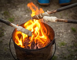 Stockbrot wird auf einem Campingplatz über einem Feuereimer gebacken
 / © Foto: Georg Berg