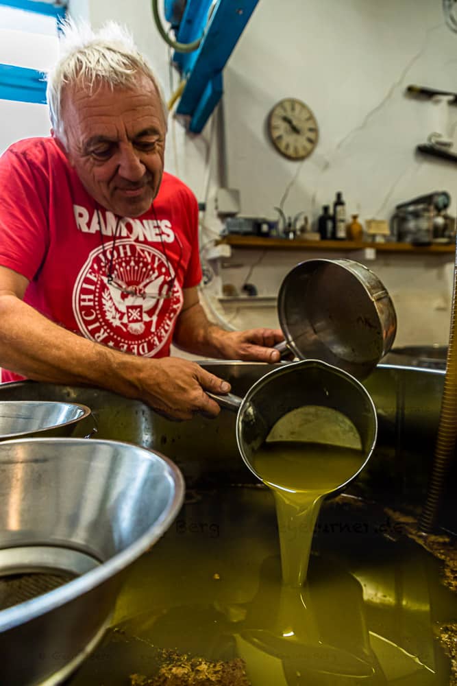 Nach dem Pressvorgang, steht das Wasser-Öl-Gemisch in offenen Behältern. Nach gut einer Stunde beginnt Fabrice Godet damit, das oben schwimmende Olivenöl abzuschöpfen. Das Fruchtwasser sinkt nach unten / © Foto: Georg Berg