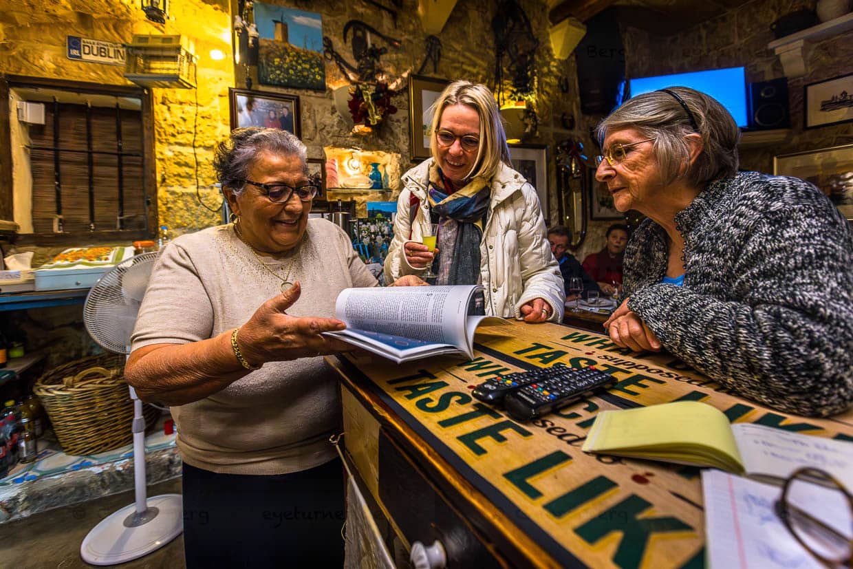 Rosina Tabone with guests at the counter of her restaurant. The room has only a few tables and is popular with villagers and guests from Malta for the traditionally cooked national dishes fenek (rabbit) and lampuki (dolphinfish) / © Photo: Georg Berg