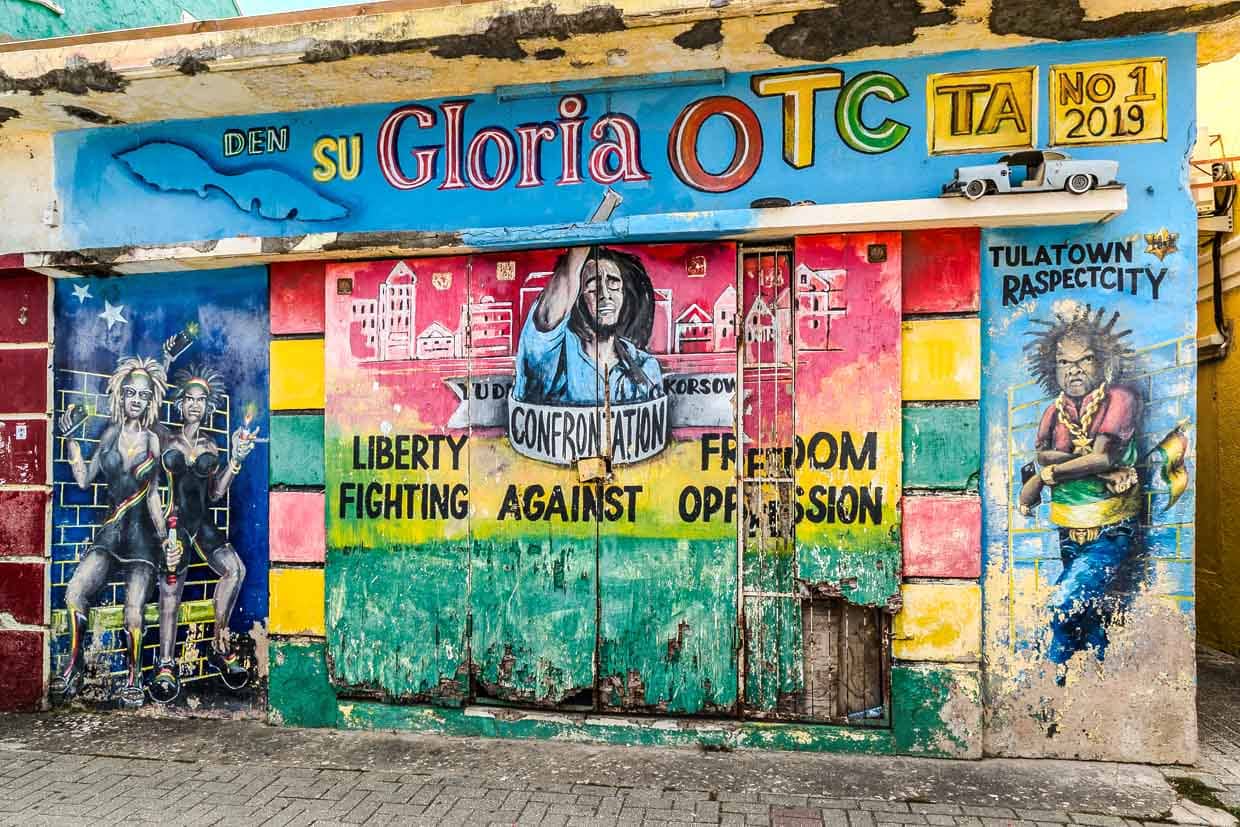 La fachada de una tienda atrincherada con tablas sirve de superficie de pintura para cambiar murales / © Foto: Georg Berg
