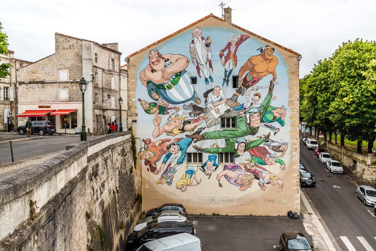 Das Wandgemälde Der Kosmos von Uderzo von François Boucqs zeigt Albert Uderzo, den Zeichner von Asterix und Co-Schöpfer (zusammen mit René Goscinny) der berühmtesten Gallier der Welt, an seinem Zeichentisch. Aus der Tischplatte explodieren förmlich die Figuren, die Generationen von Lesern geprägt haben – eine perfekte Metapher für die kreative Schöpferkraft des Künstlers / © Foto: Georg Berg