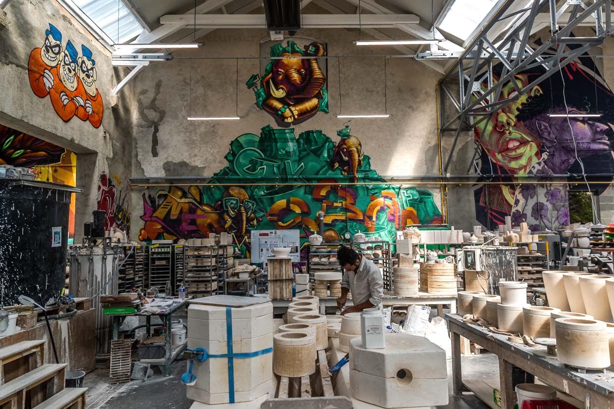 Kunstporzellanwerkstatt Ateliers Arquié in Limoges, Die Werkstatt kombiniert traditionelles Handwerk mit modernen Formen, Farben und Techniken. Das Atelier ist in ehemaligen Spinnerei- und Webereigebäuden am Ufer der Vienne untergebracht, an den Wänden großformatige Graffiti-Arbeiten von regionalen Künstlern / © Foto: Georg Berg