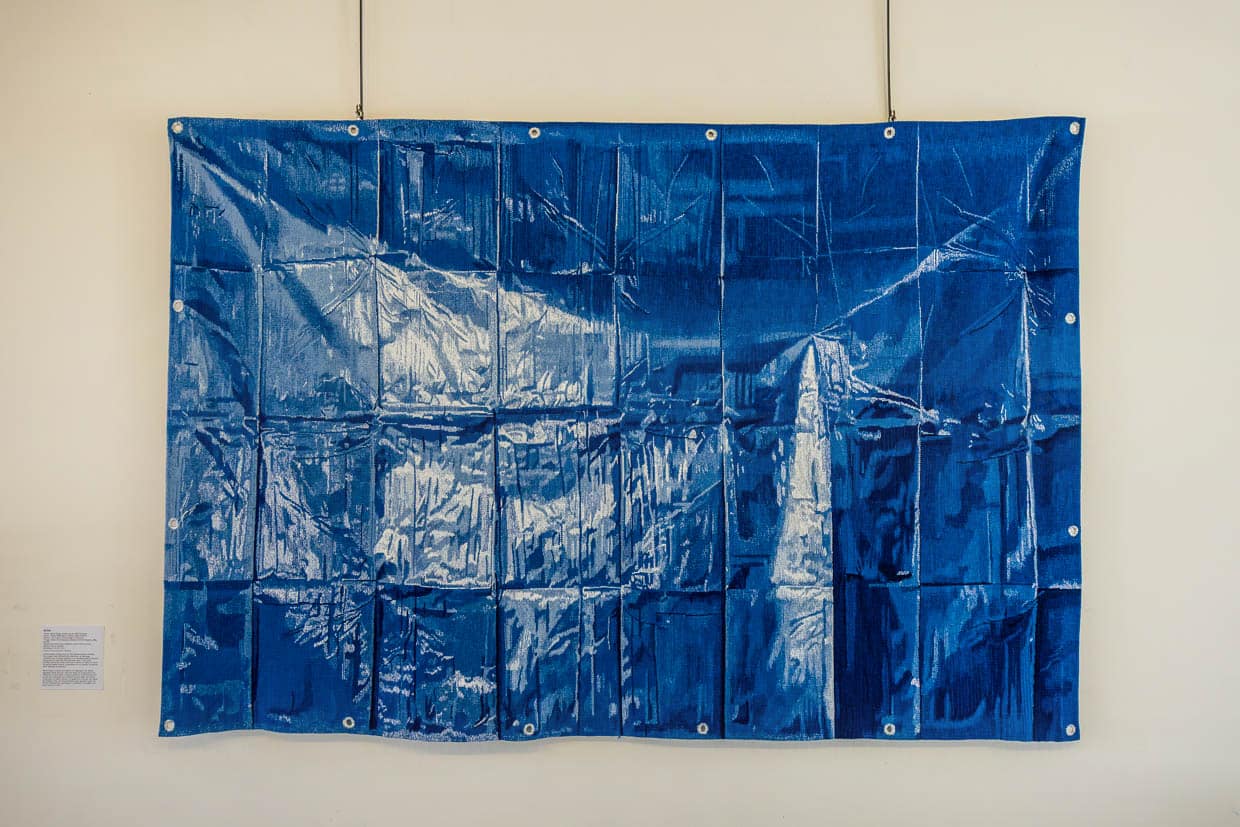 Die Kunst der optischen Täuschung. Dies ist keine Plastikplane sondern ein Wandteppich. „Blue“ von Marie Sirgue. Bei näherer Betrachtung wird aus der glänzenden Plastikplane ein perfekt gewebter und flacher Teppich aus Seide in 3 Meter x 2 Meter / © Foto: Georg Berg